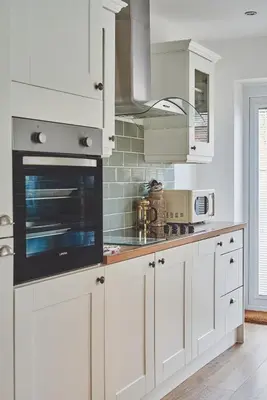 a kitchen with white cabinets and a stove top oven at Hollie Cottage in Lytham St Annes