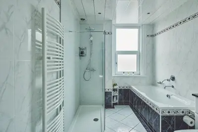 a white bathroom with a tub and a sink at Hollie Cottage in Lytham St Annes