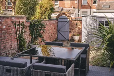 a patio with a table and chairs and a door at Hollie Cottage in Lytham St Annes