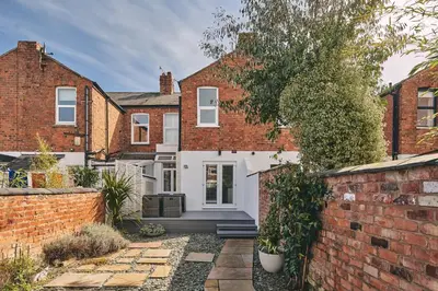 a home with a brick wall and a white door at Hollie Cottage in Lytham St Annes