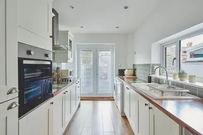 a kitchen with white cabinets and a large appliance at Hollie Cottage in Lytham St Annes