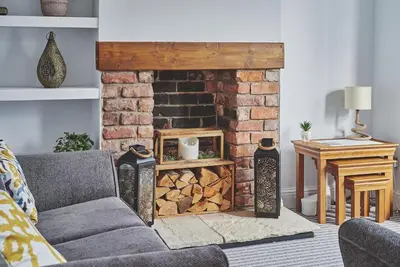 a living room with a couch and a brick fireplace at Hollie Cottage in Lytham St Annes