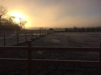 a fence in a field with the sunset in the background at The Bungalow in Preston