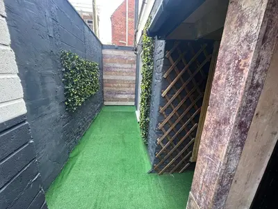 a walkway with green flooring and a brick wall at The White House New York Suites in Blackpool
