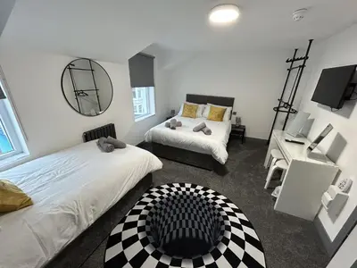 a bedroom with two beds and a mirror at The White House New York Suites in Blackpool