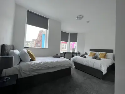 two beds in a room with two windows at The White House New York Suites in Blackpool