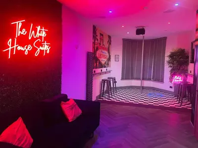 a living room with a couch and a neon sign at The White House Vegas Suites in Blackpool