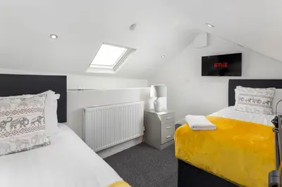a bedroom with two beds and a clock on the wall at Teck House - Air Host & Stay - 5 mins to Hospital in Liverpool
