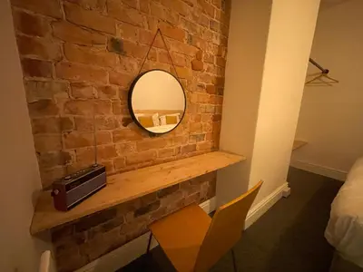 a room with a brick wall with a mirror at Magenta Melodies, 5 Bedroom House in Blackpool