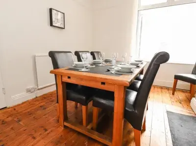 a wooden table with black chairs and wine glasses at Magenta Melodies, 5 Bedroom House in Blackpool