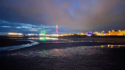 a beach at night with a ferris wheel in the distance at Magenta Melodies, 5 Bedroom House in Blackpool