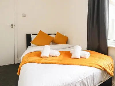 a bed with two stuffed animals on top of it at Magenta Melodies, 5 Bedroom House in Blackpool