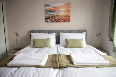 a bedroom with a bed with white sheets and pillows at Wave Stays - Ground Floor Apartment - Outside Seating Area in Cleveleys