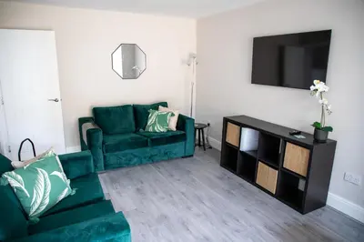 a living room with a green couch and a tv at Wave Stays - Ground Floor Apartment - Outside Seating Area in Cleveleys