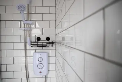 a white tiled bathroom with a shower and a shower head at Wave Stays - Ground Floor Apartment - Outside Seating Area in Cleveleys