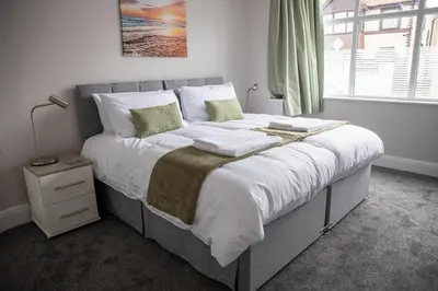 a bedroom with a large bed with white sheets and green pillows at Wave Stays - Ground Floor Apartment - Outside Seating Area in Cleveleys