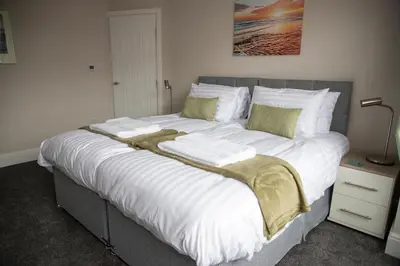 a large bed with white sheets and green pillows at Wave Stays - Ground Floor Apartment - Outside Seating Area in Cleveleys