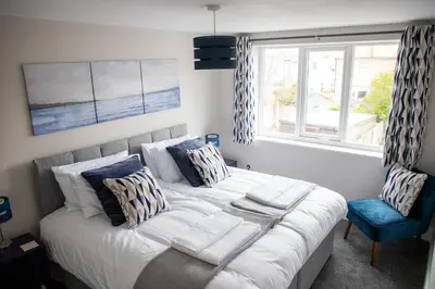 a bedroom with a large bed and a blue chair at Wave Stays - First Floor Apartment - Heart of Cleveleys in Cleveleys