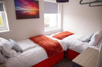 two beds in a room with two windows at Wave Stays - First Floor Apartment - Heart of Cleveleys in Cleveleys