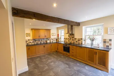 a large kitchen with wooden cabinets and a window at Entire cottage & private garden in Scorton in Scorton