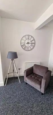 a couch in a room with a clock on the wall at LFC Anfield Guest House in Liverpool