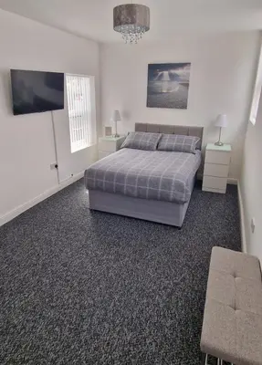 a bedroom with a bed and a flat screen tv at LFC Anfield Guest House in Liverpool