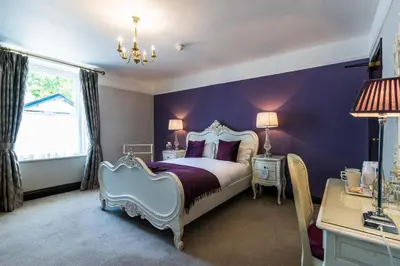 a bedroom with a bed and a purple wall at The Swan Hotel in Clitheroe