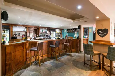 a bar in a pub with wooden bar stools at The Swan Hotel in Clitheroe