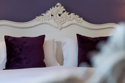 a bedroom with a white bed with purple pillows at The Swan Hotel in Clitheroe