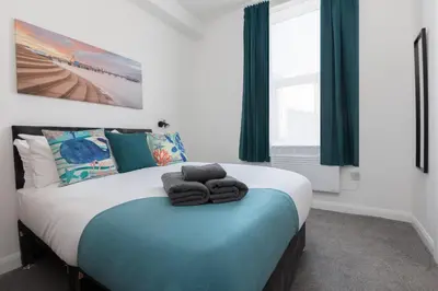 a bedroom with a bed with towels on it at Charles Alexander Short Stay - TheWestern Blackpool in Blackpool