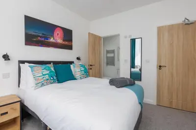 a bedroom with a large white bed and a wooden door at Charles Alexander Short Stay - TheWestern Blackpool in Blackpool