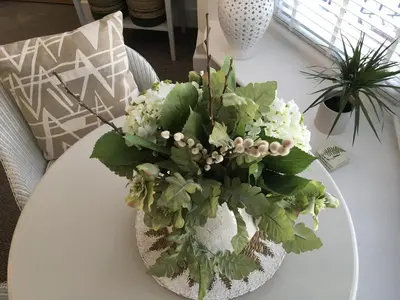 a white vase with white flowers on a table at The Bungalow and Studio Apartments in Lytham St Annes