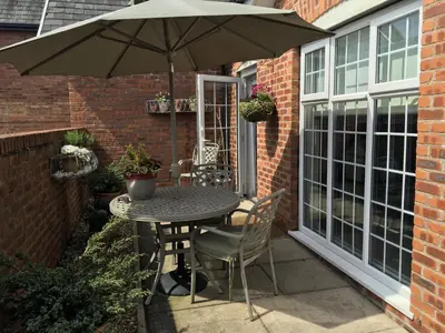 a table and chairs with an umbrella on a patio at The Bungalow and Studio Apartments in Lytham St Annes