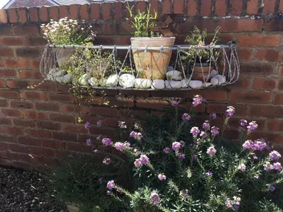 a brick wall with three potted plants and flowers at The Bungalow and Studio Apartments in Lytham St Annes