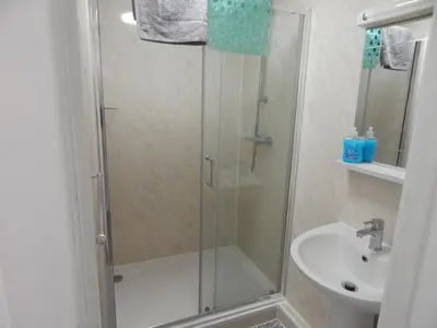 a shower with a glass door next to a sink at Llanryan Guest House in Blackpool