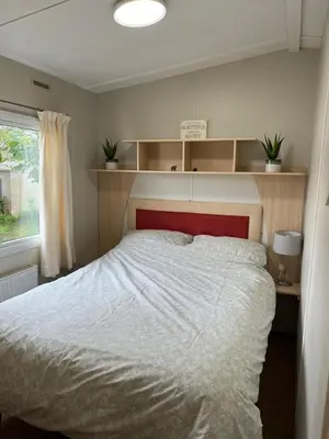 a bedroom with a bed with a red headboard and a window at Marina Retreat in Haverigg
