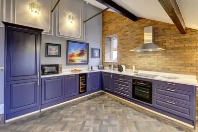 a kitchen with purple cabinets and a brick wall at Swish Luxury Holiday Apartments in Blackpool