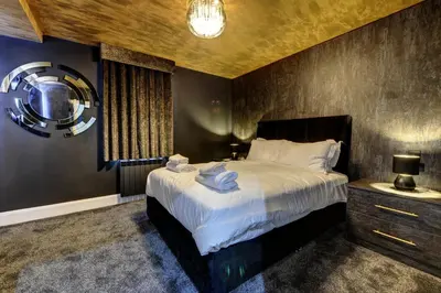 a bedroom with a large bed and a mirror at Swish Luxury Holiday Apartments in Blackpool