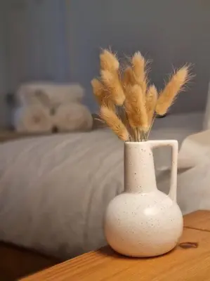 a white vase with feathers in it on a table at Cosy modern house in Liverpool