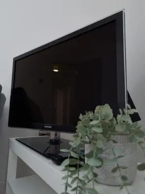 a computer monitor and a vase with flowers on a table at Cosy modern house in Liverpool