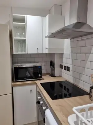 a kitchen with white cabinets and a black microwave at Cosy modern house in Liverpool