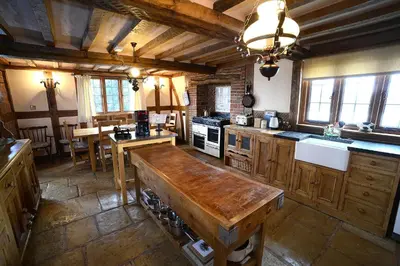 a large kitchen with wooden cabinets and a table at FLETCHERS HALL COVERED POOL Heated in Freckleton