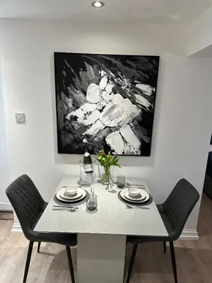 a dining room table with two chairs and a painting on the wall at The Cottage in Saint Annes on the Sea