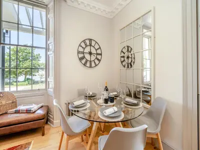 a dining room with a table and chairs and a clock at Mishmash in Arnside