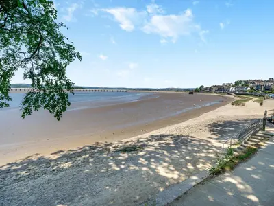a sandy beach with a bridge in the distance at Mishmash in Arnside