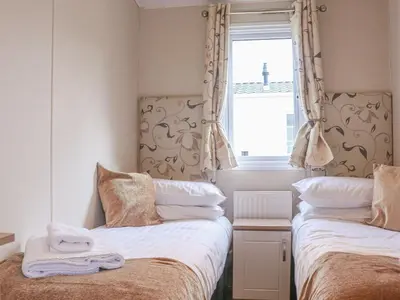 a bedroom with two beds and a window with a lighthouse at Tiptoes Lodge in Carnforth