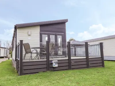a house with a deck with a table on it at Tiptoes Lodge in Carnforth