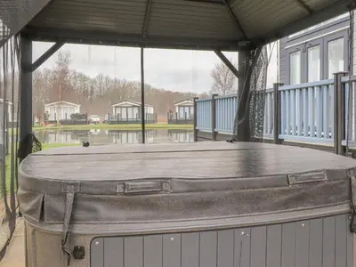 a hot tub sitting on a covered porch with water at Tiptoes Lodge in Carnforth
