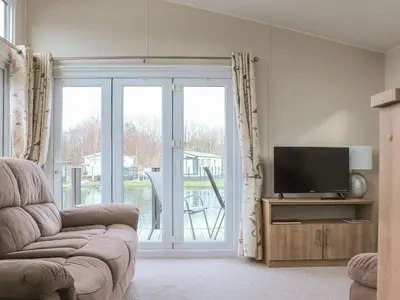 a living room with a tv and a sliding glass door at Tiptoes Lodge in Carnforth