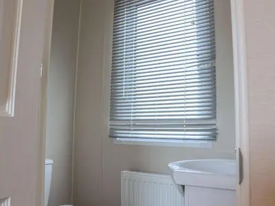 a bathroom with a white sink and a window at Tiptoes Lodge in Carnforth